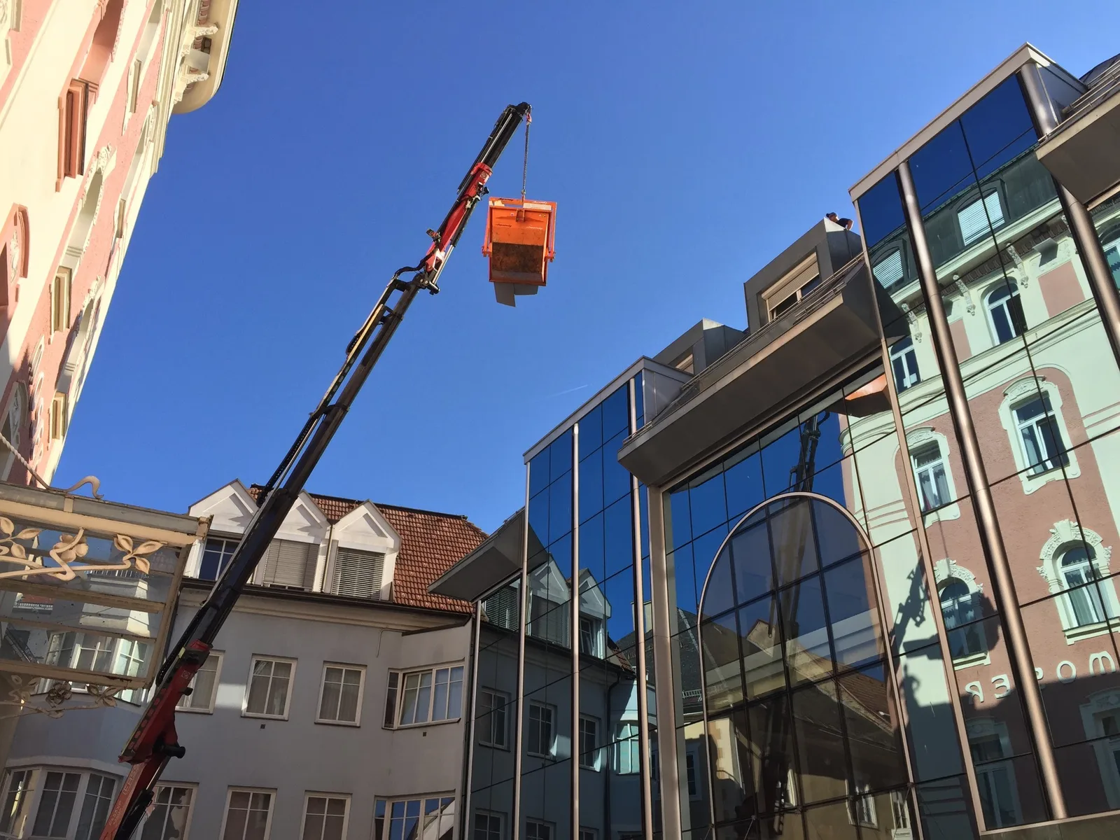Autokran mit Arbeitskorb an einem Dach in der Innenstadt