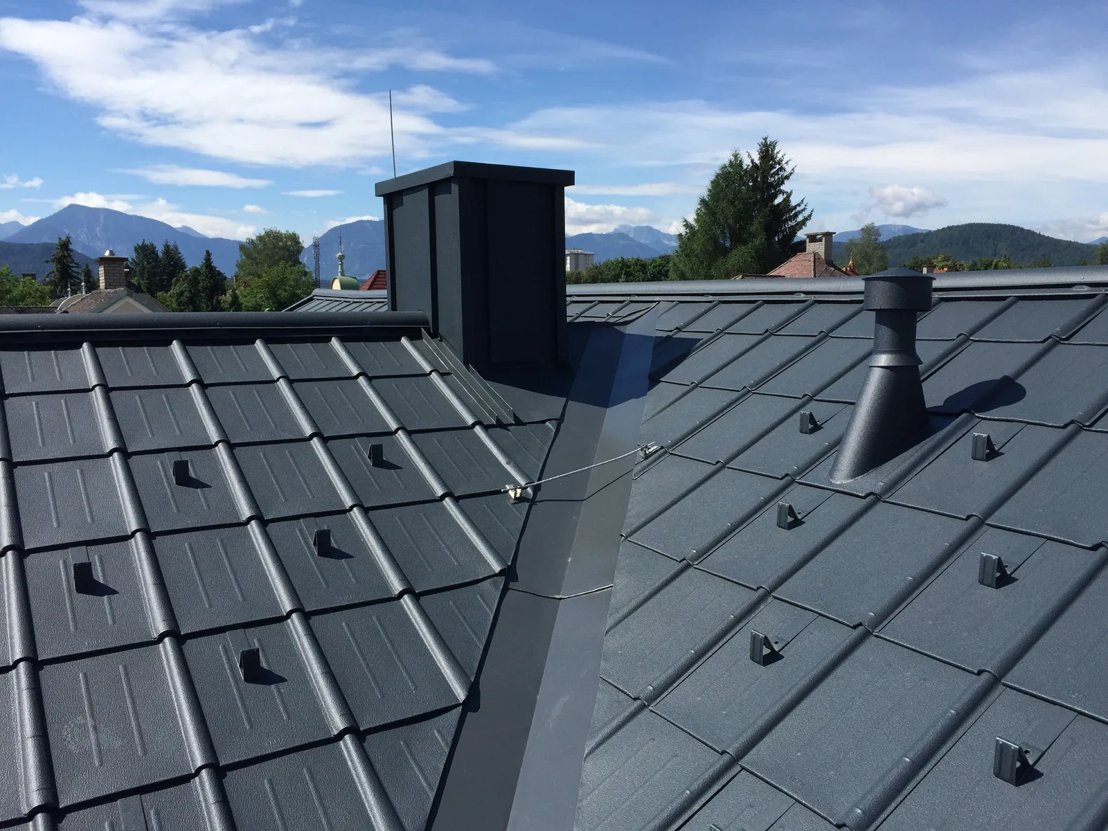 Anthrazitfarbene Prefa-Dachplatten mit Schneefang und eingefasstem Kamin